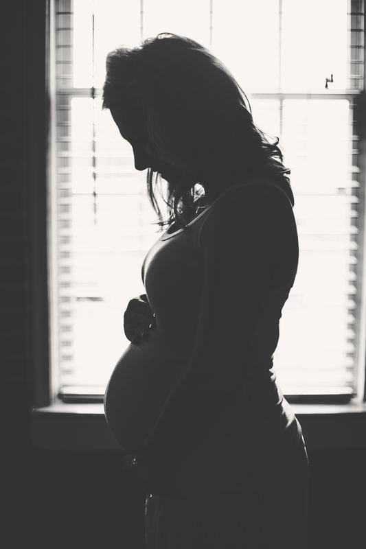 Silhouet van een zwangere vrouw aan het raam